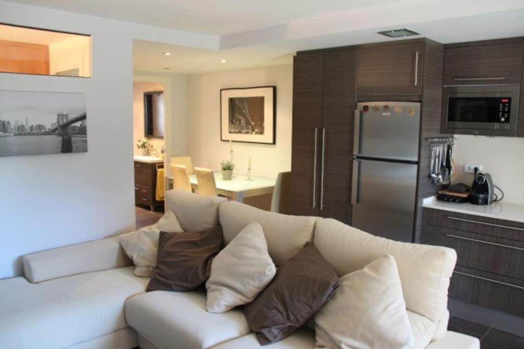 a living room with a white couch and a kitchen at Apartamento cerca pista de esqui La Molina con piscina y Jardín in La Molina