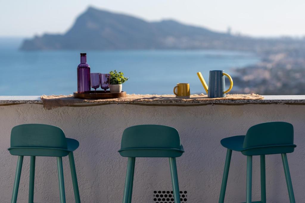 three green stools on a bar with a view at Casa Blanca in Alicante