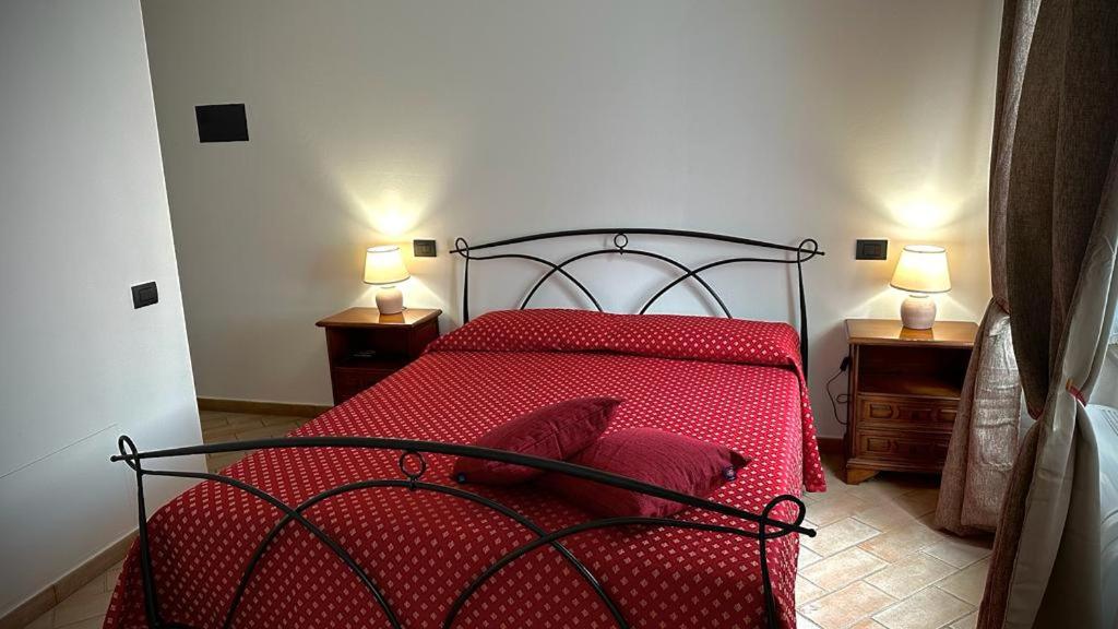 um quarto com uma cama vermelha com duas mesas de cabeceira em La Cattedrale Rooms em Assis