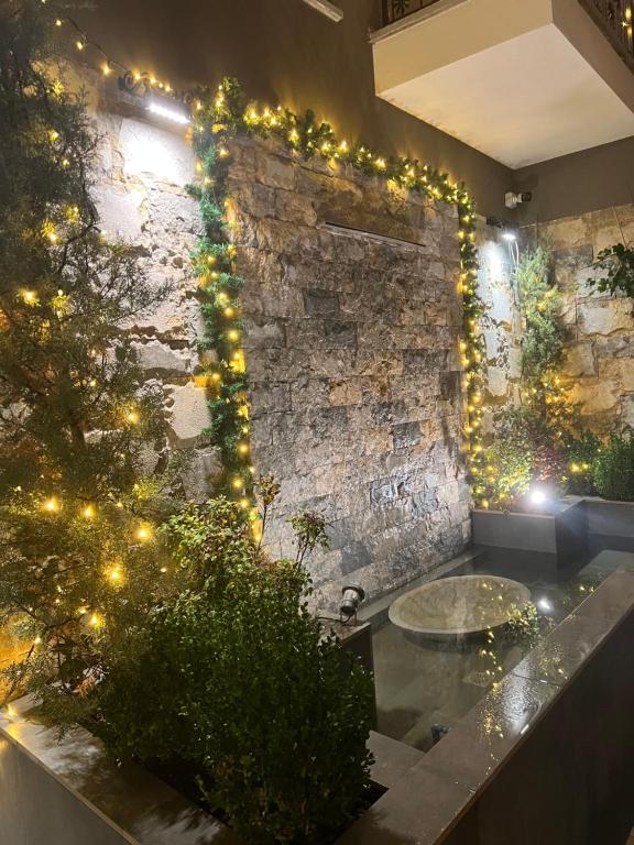 La salle de bains est pourvue d'un mur en pierre avec des lumières de Noël. dans l'établissement Alma Rose Apartment, à Korçë