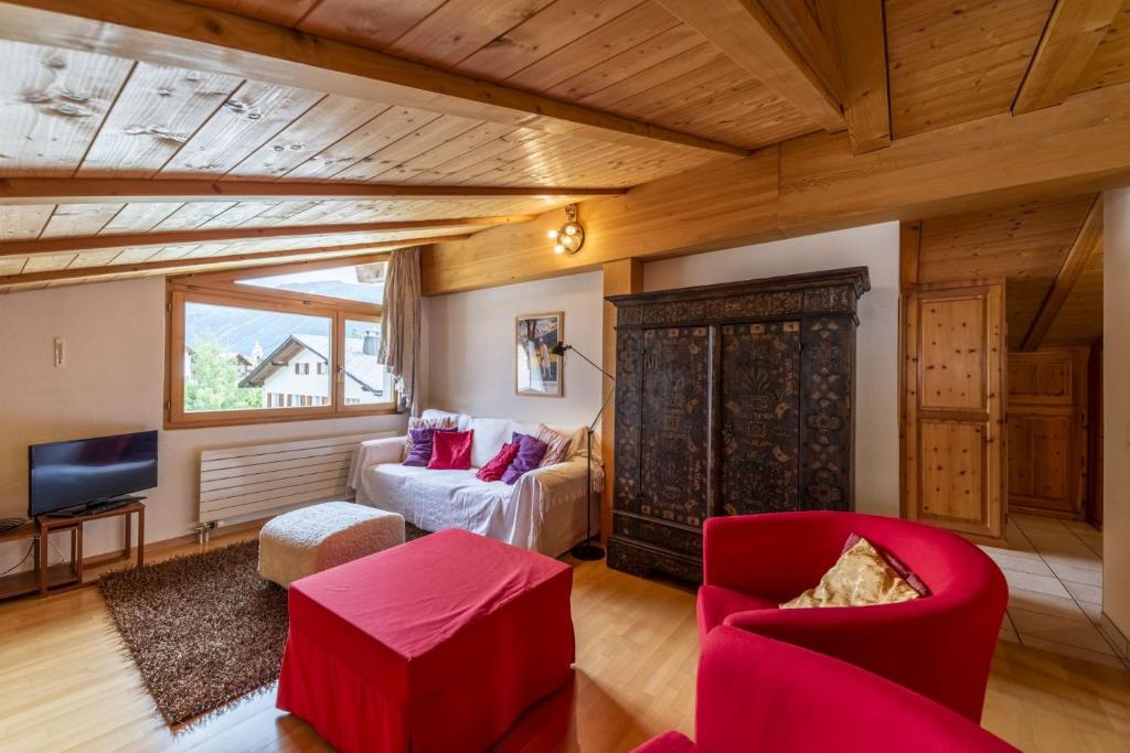 uma sala de estar com mobiliário vermelho e uma grande janela em Chesa Susi - Celerina em Celerina