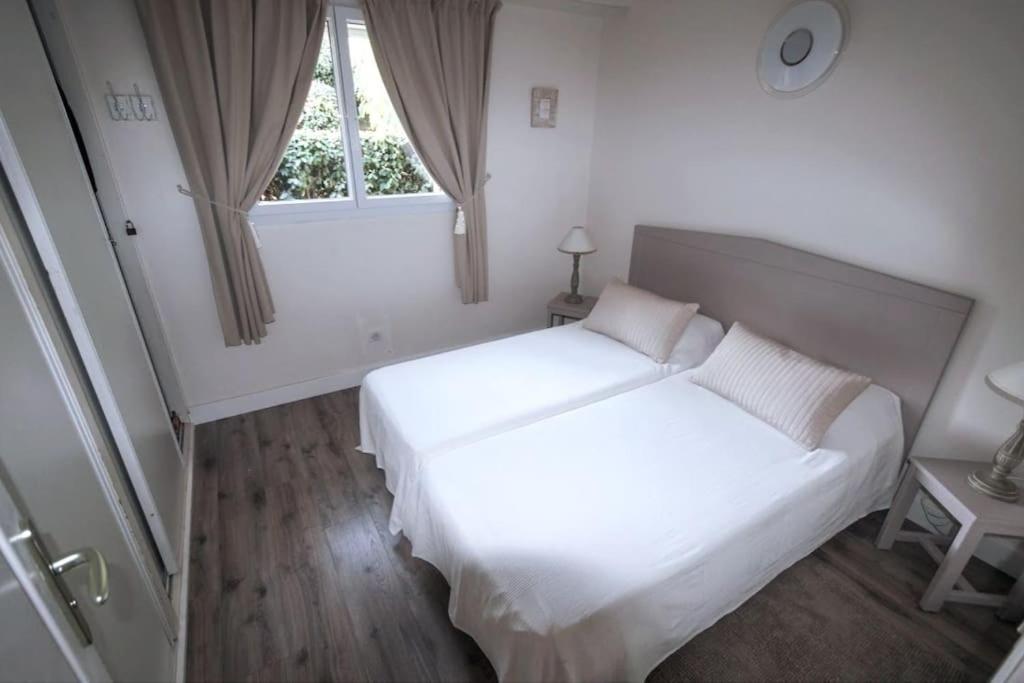 a white bedroom with a large bed and a window at Villa Porto vecchio vue mer 5 étoiles piscine parking privé gratuit in Porto-Vecchio