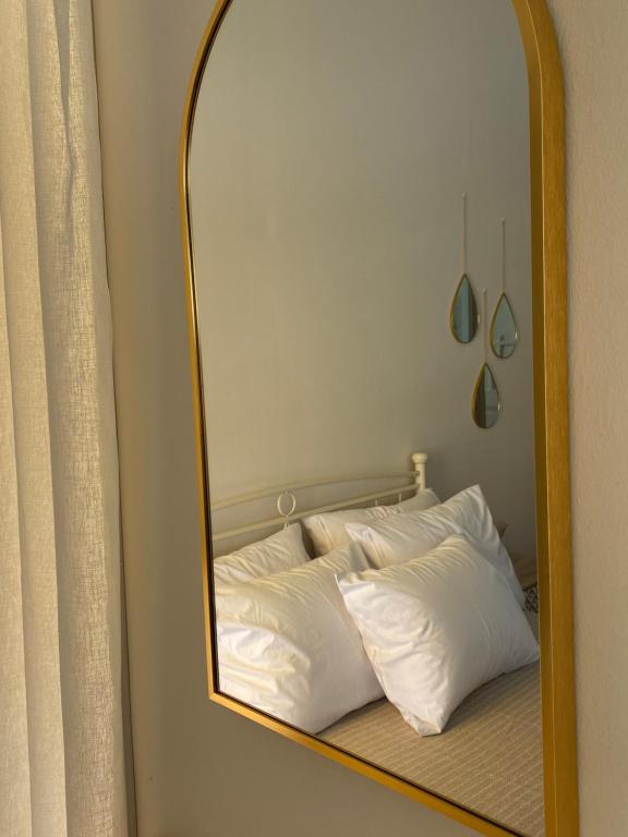 a mirror reflecting a bed with white pillows at The Art House By The Sea in Plomarion