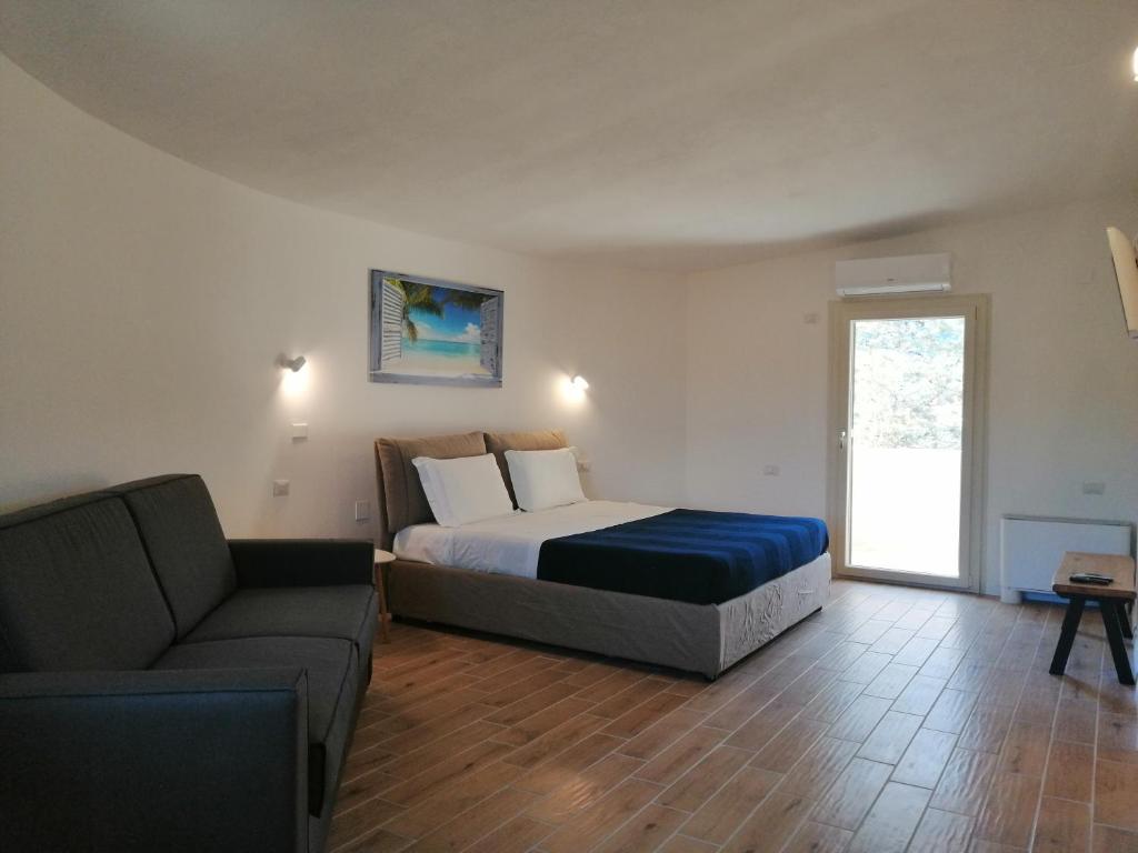 1 dormitorio con cama, sofá y ventana en B&B Villa Zola en Capoterra