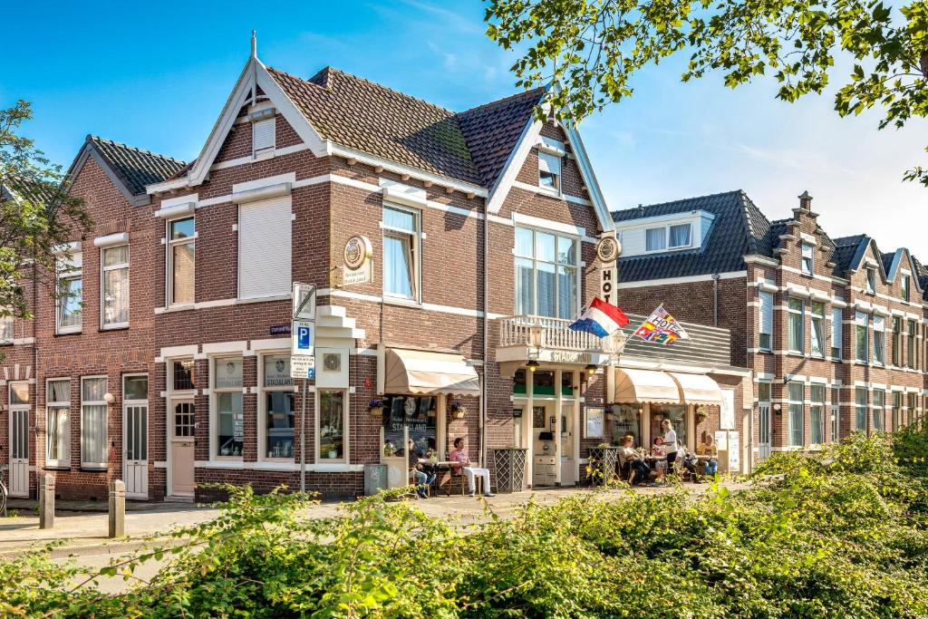 een groot bakstenen gebouw waar mensen buiten zitten bij Hotel Stad en Land in Alkmaar