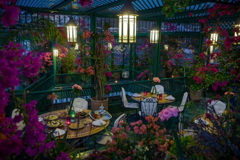 un jardín con mesas, sillas y flores en Riad La Maison Verte, en Fez