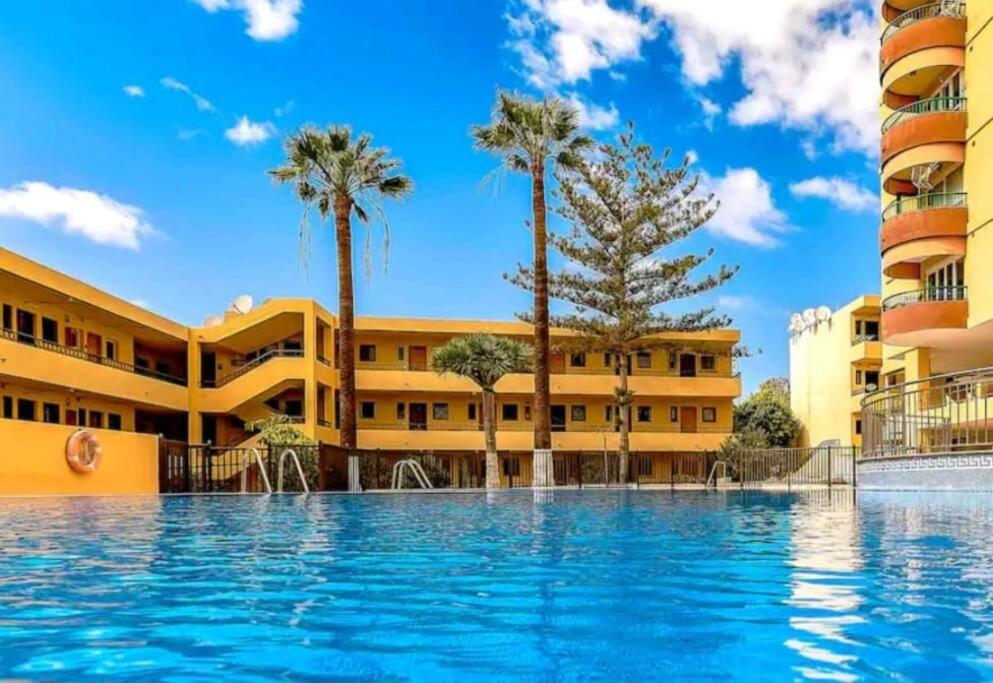 - une piscine en face d'un bâtiment avec des palmiers dans l'établissement Estudio coqueto Torres del Sol, à Arona