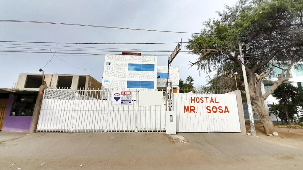 a white fence with a sign in front of a building at HOSTAL MISTER SOSA in Ica