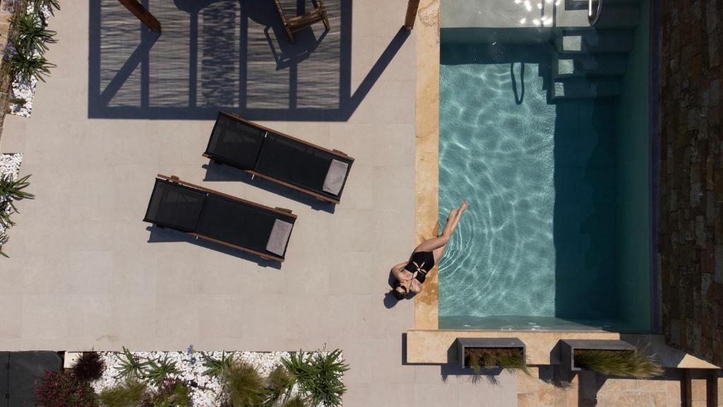 a person is standing next to a swimming pool at Pnoes Luxury Suites in Paliouri