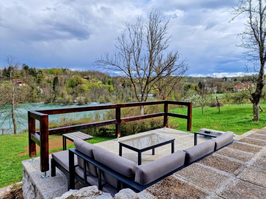 a patio with a bench and a table and a lake at Pixie House - Mrežnica, private pier, hot tub in Gornji Zvečaj