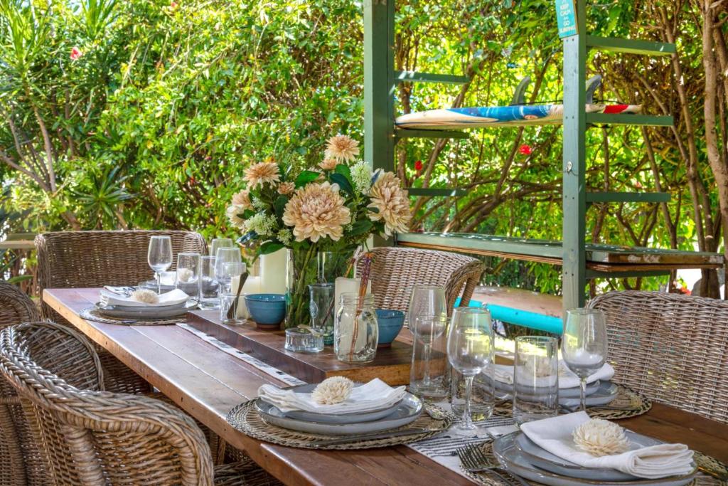 a wooden table with plates and glasses and flowers at KBM Resorts International Colony Club ICC-11 2Bdm in Kaanapali