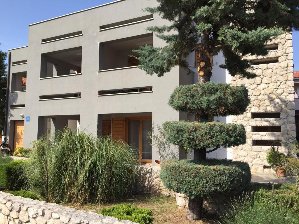 a building with a tree in front of it at Apartments Smiljanic in Tribunj