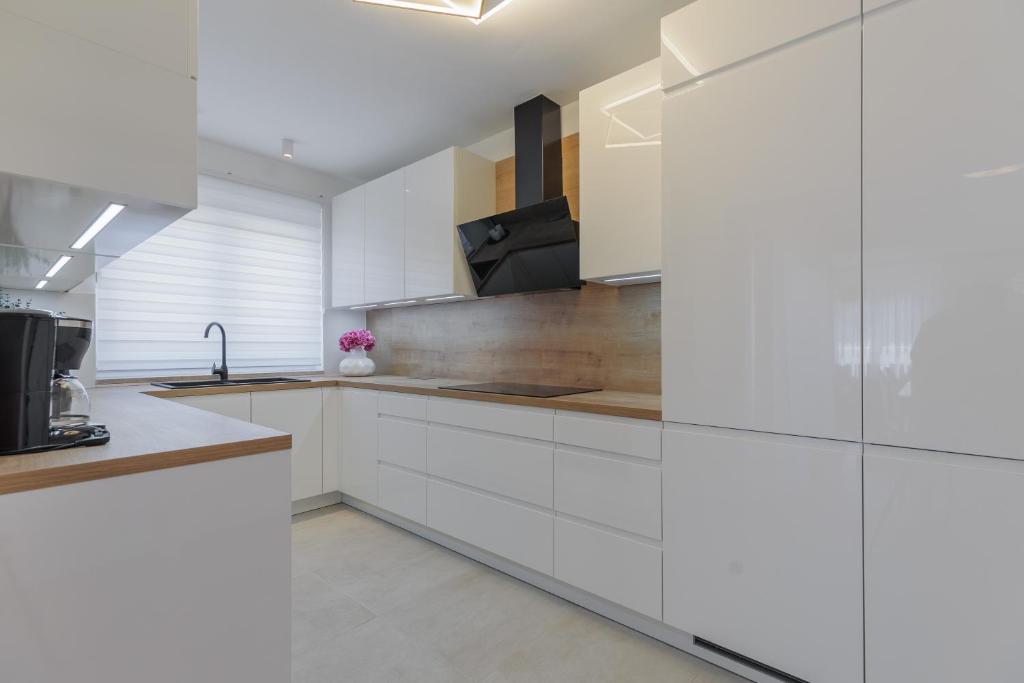 a white kitchen with white cabinets and a sink at Apartments Rusula Zadar in Zadar