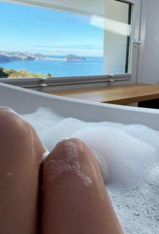 a persons feet in a bath tub with a window at Hotel Boutique Berazadi Berri in Zarautz