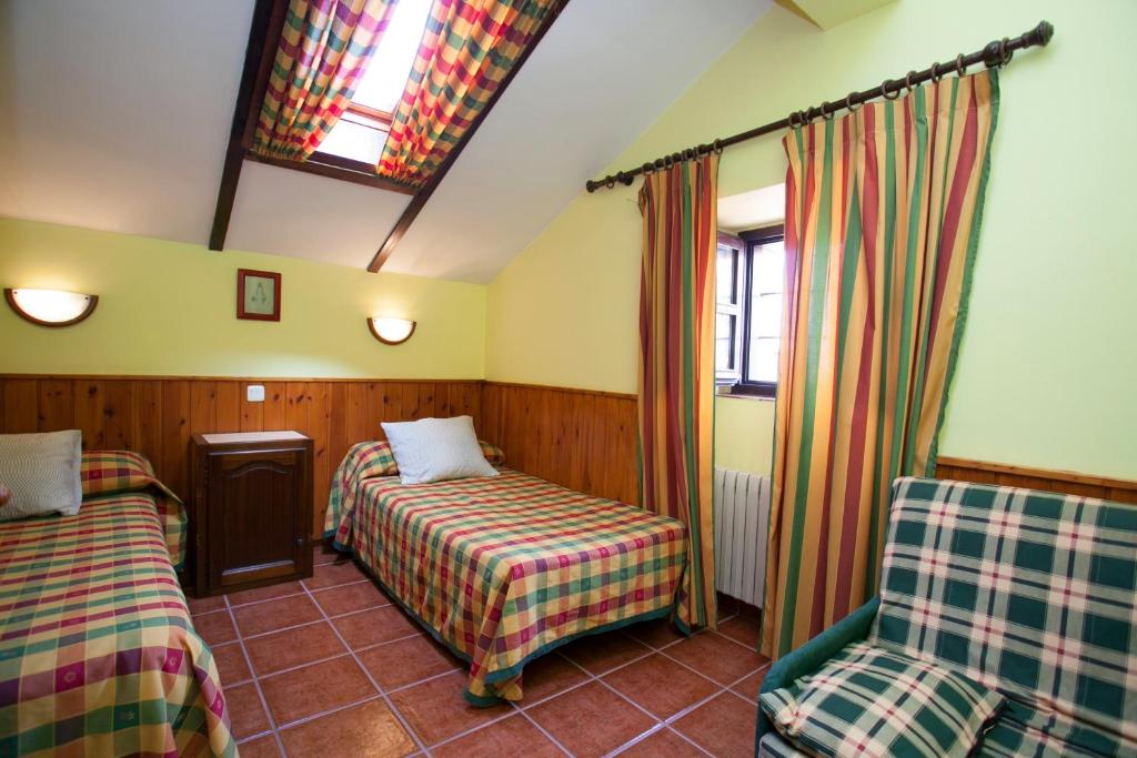 Habitación con 2 camas y una silla. en Nuestra Señora del Carmen, en San Sebastián de Garabandal