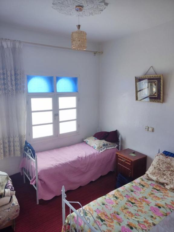 1 dormitorio con 2 camas y ventana en Casa Fahssi, en Chefchaouen