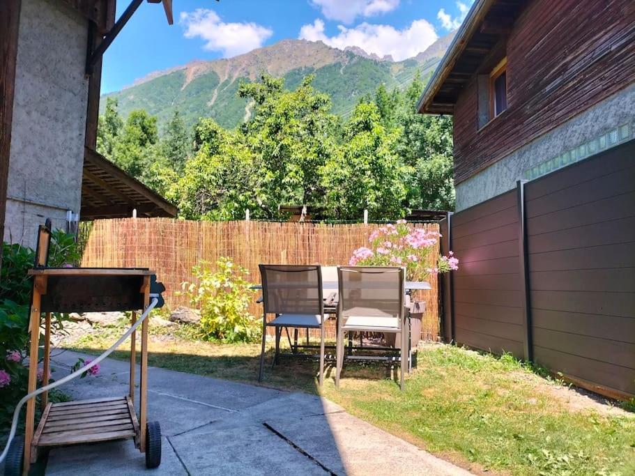 deux chaises assises dans une cour à côté d'une clôture dans l'établissement Appartement pour 4prs dans maison individuelle, à Allemont