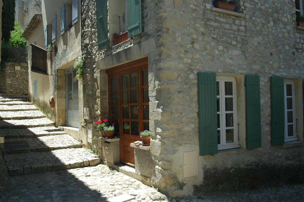 um edifício de pedra com persianas verdes e uma porta de madeira em Annapurna Bed & Breakfast em Vaison-la-Romaine