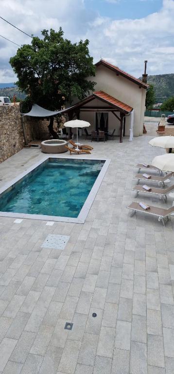 una piscina con sillas, una sombrilla y una casa en House KID en Bribir