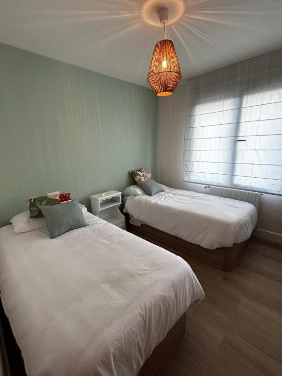 um quarto com duas camas e um lustre em Ático en Llanes con terraza junto Paseo San Pedro em Llanes