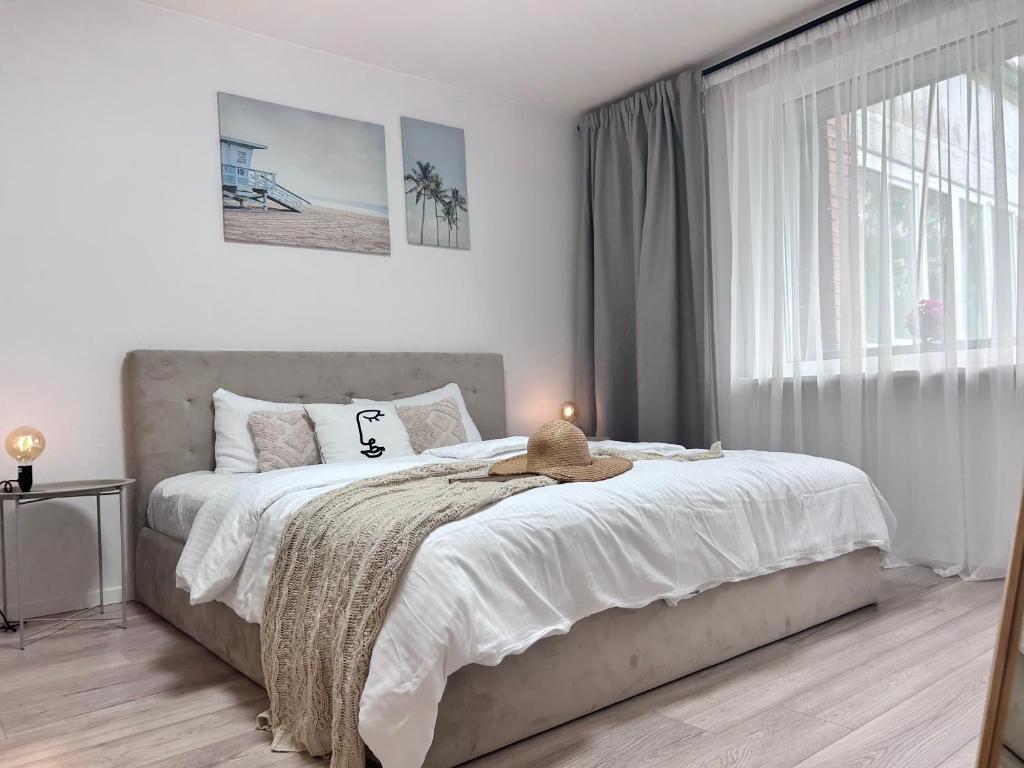 - une chambre avec un lit doté de draps blancs et une fenêtre dans l'établissement 2 bedrooms apartment, city center, with balconies, à Palanga