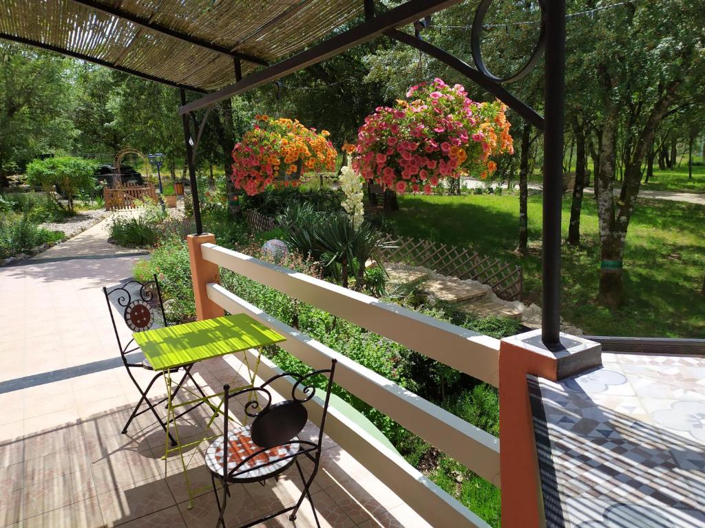 - une terrasse couverte avec une table, des chaises et des fleurs dans l'établissement Le Mas de Balmes, à Vers