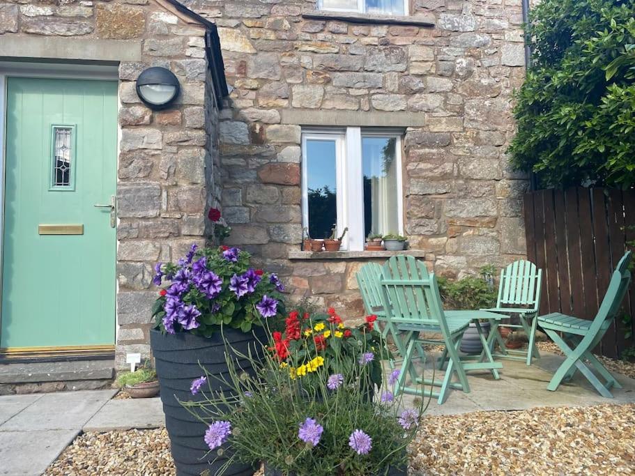a stone house with two chairs and a table and flowers at Idillic Two bed country cottage in Kirkby Thore
