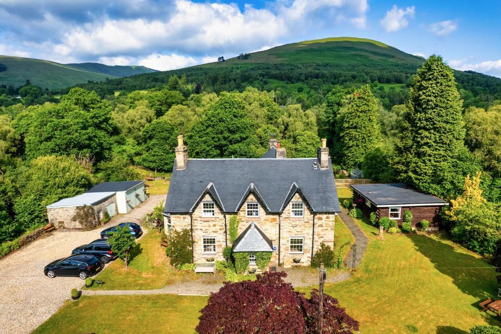 an old stone house with cars parked in front of it at Mansewood Country House in Lochearnhead