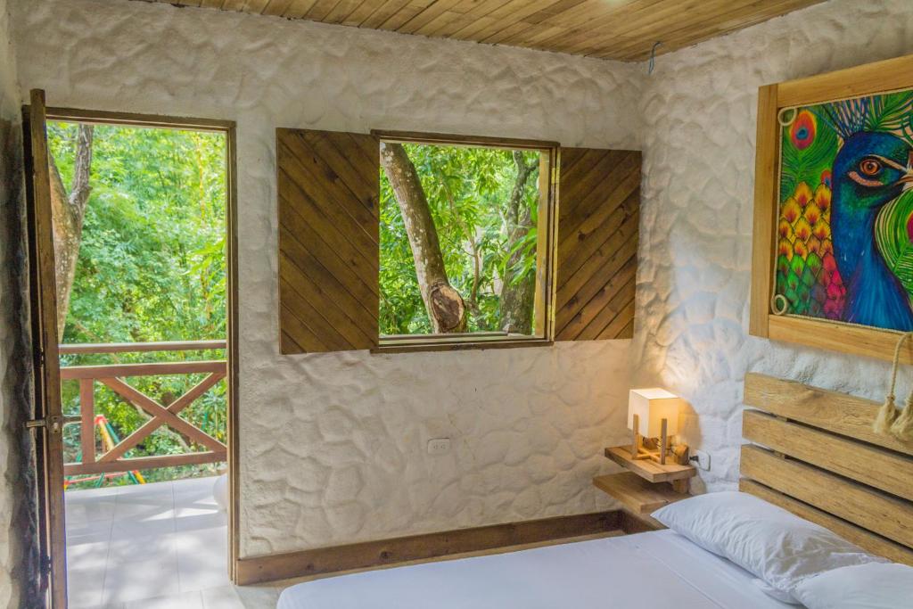 a bedroom with a bed and a window with a painting at Hotel Cabañas Club Sierra Limón in Santa Marta