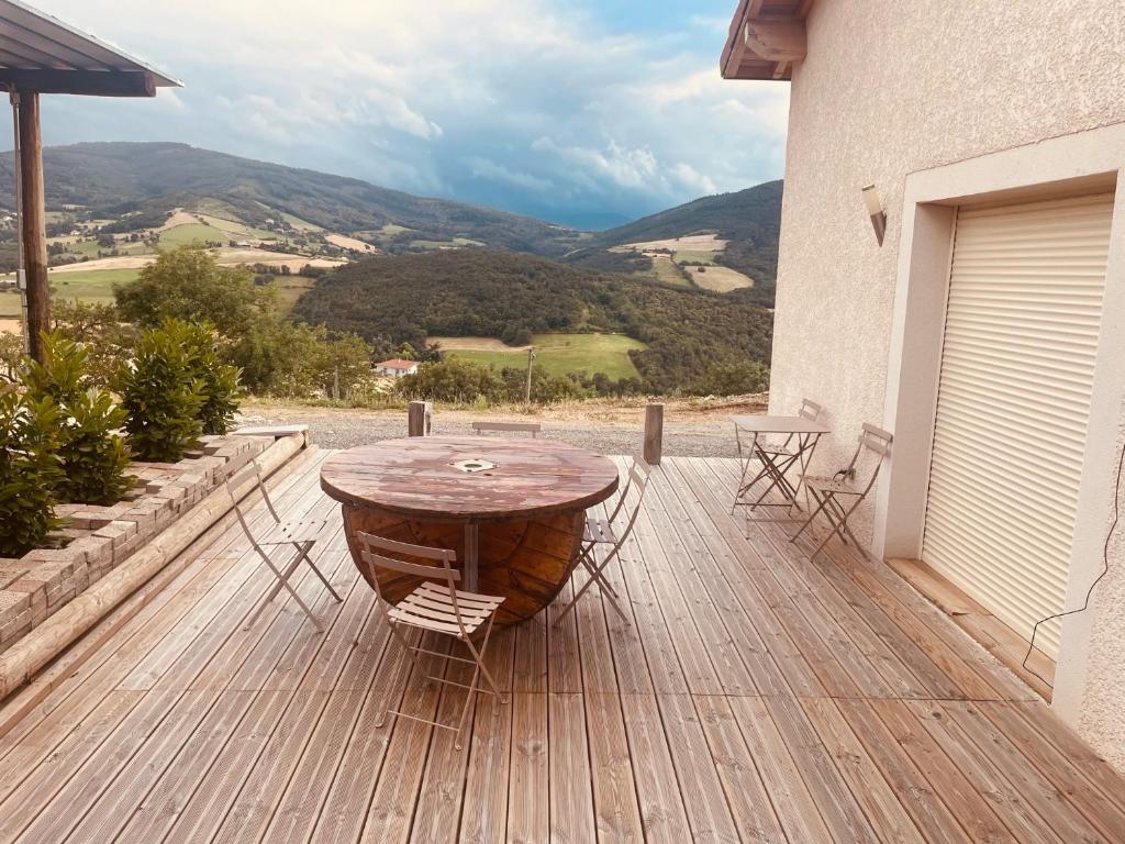 una terrazza in legno con tavolo e sedie. di les rouardes a Sainte-Croix-en-Jarez