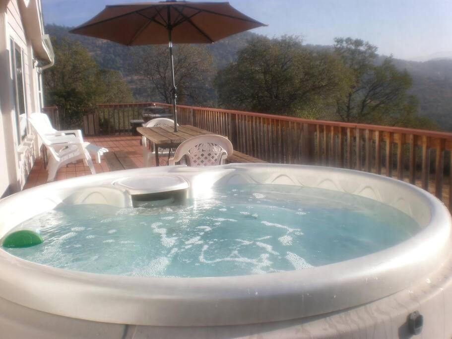 a hot tub on a deck with an umbrella at Mariposa Ridge Retreat in Mariposa