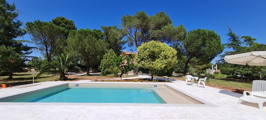 a swimming pool with two chairs and an umbrella at Villa Morea-Relax in piscina in Putignano