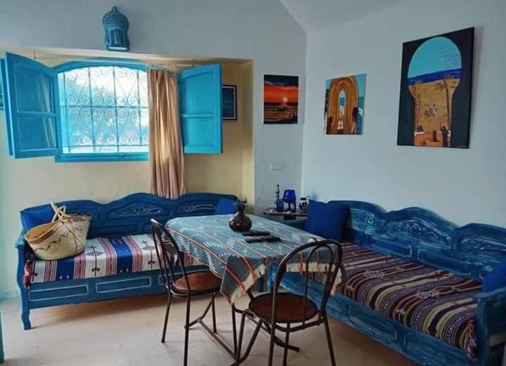 um quarto com uma cama, uma mesa e cadeiras em Bungalow Djerbien em Midoun