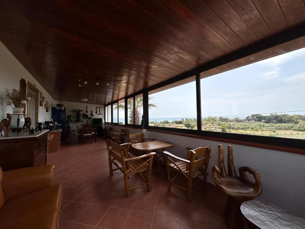 a dining room with a table and chairs and windows at La Foggia seaside paradise in Siculiana
