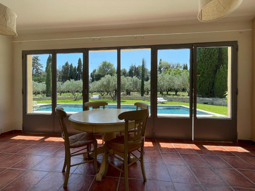 a dining room with a table and chairs and a pool at MAS MILLÉSIME - Chambre double - petit déjeuner - piscine - Mas du XVIIIème siècle proche Saint-Rémy-de-Provence in Mas blanc des Alpilles