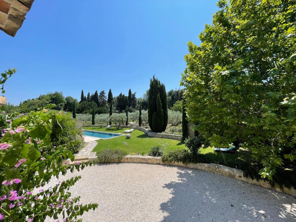 a garden with a swimming pool and trees at MAS MILLÉSIME - Chambre double - petit déjeuner - piscine - Mas du XVIIIème siècle proche Saint-Rémy-de-Provence in Mas blanc des Alpilles