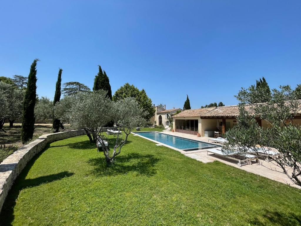 a garden with a swimming pool and a house at MAS MILLÉSIME - Chambre double - petit déjeuner - piscine - Mas du XVIIIème siècle proche Saint-Rémy-de-Provence in Mas blanc des Alpilles