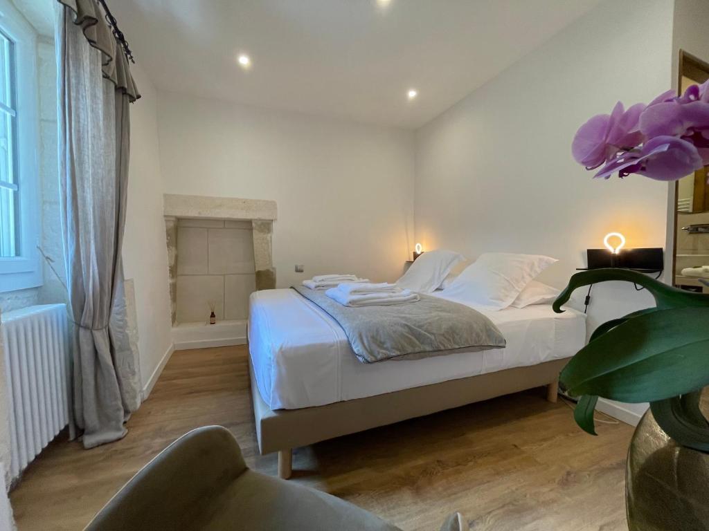 a white bedroom with a bed and a chair at MAS MILLÉSIME - Chambre double - petit déjeuner - piscine - Mas du XVIIIème siècle proche Saint-Rémy-de-Provence in Mas blanc des Alpilles