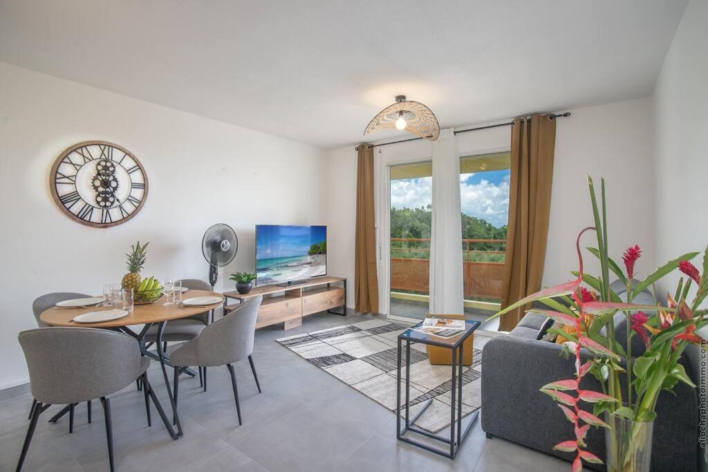 sala de estar con mesa, sillas y TV en Navira - Appartement le Pavillon, en Le Lamentin