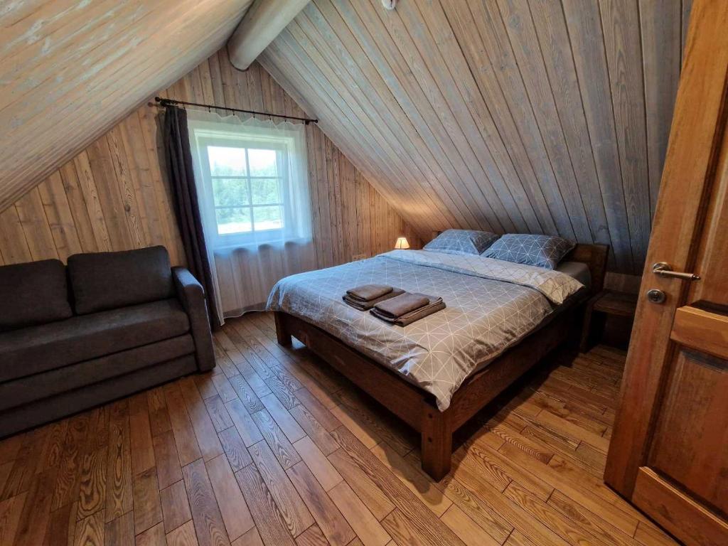 a bedroom with a bed and a couch in a attic at Anykščiai MĖNULIO AKMUO 