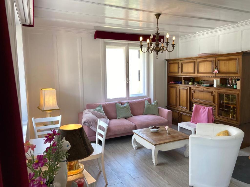 un soggiorno con divano rosa e tavolo di Chasa Sassalbo a Poschiavo