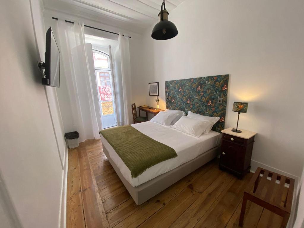 1 dormitorio con 1 cama grande y suelo de madera en União - Guest House, en Tomar