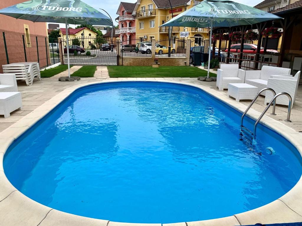 a large blue swimming pool with chairs and umbrellas at Pensiunea ALAS in Baile Felix