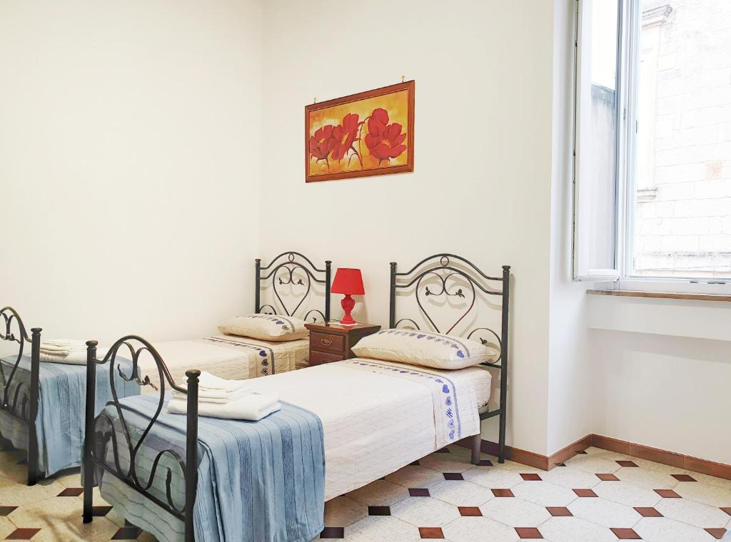 2 camas individuales en un dormitorio con ventana en Dimora Torre del Cavaliere, en Castro di Lecce