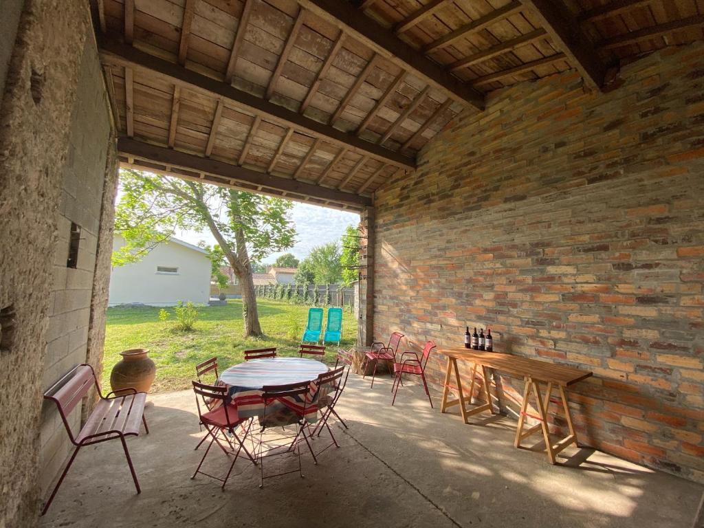 un patio avec une table et des chaises et un mur de briques dans l'établissement Alice’s house, Maison & Grange à 10km de l’Océan, à Naujac-sur-Mer