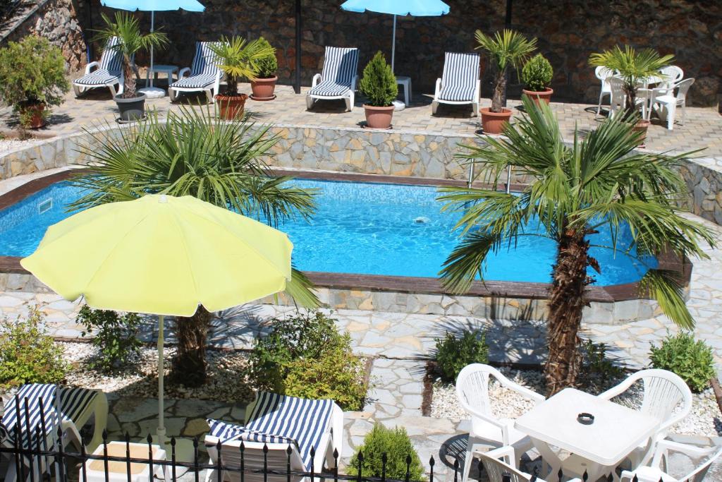 een zwembad met stoelen en een gele parasol en een tafel met een parasol bij Vila Kumani in Ohrid