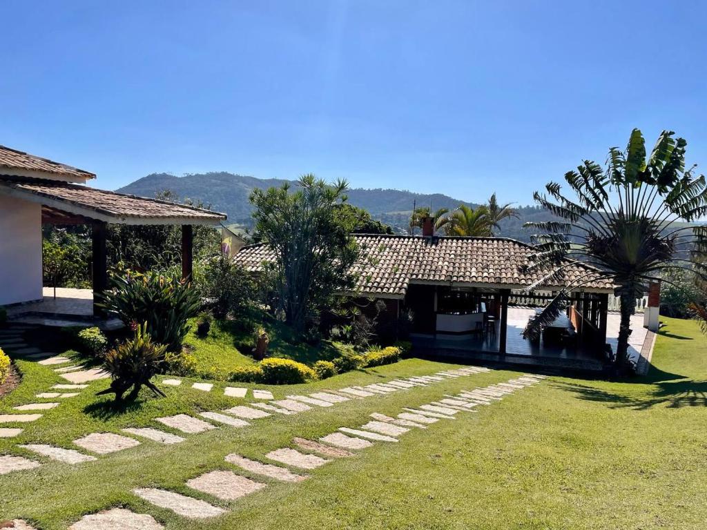 a house with a lawn and a house with palm trees at Chácara Mira Flores in Atibaia