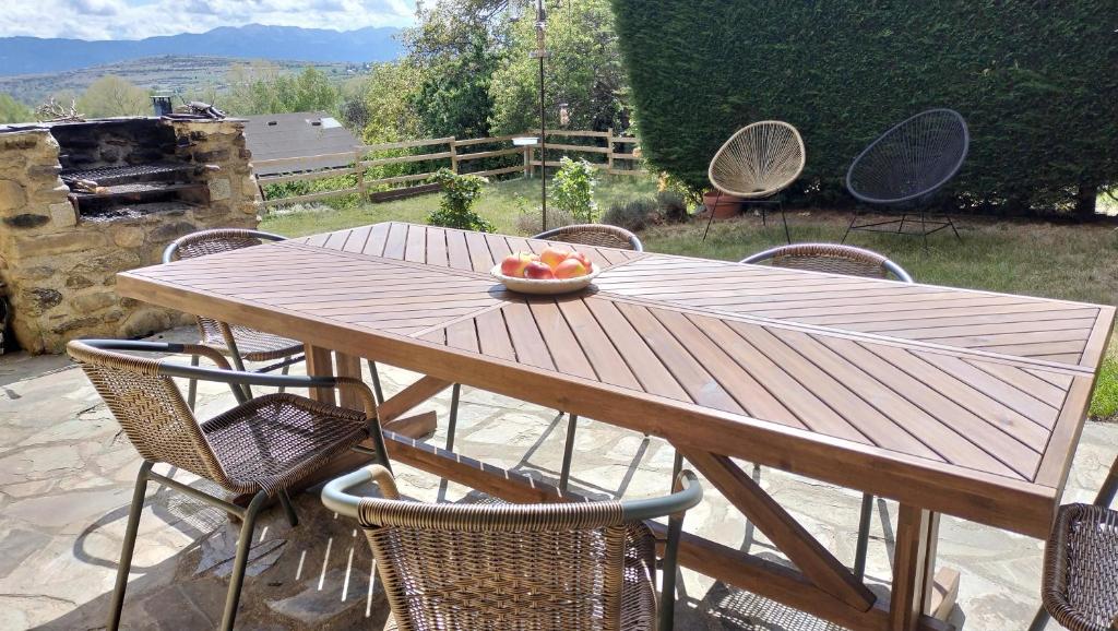 a wooden table with chairs and a bowl of fruit on it at Maison en Cerdagne avec belle vue in Enveitg