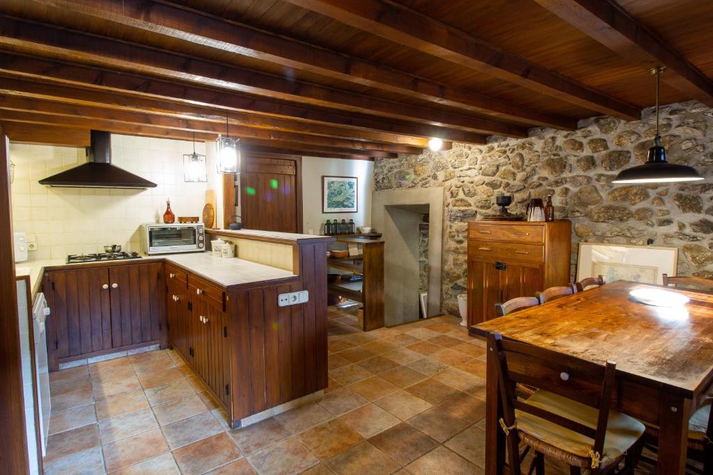 a kitchen with wooden cabinets and a table in it at Maison en Cerdagne avec belle vue in Enveitg