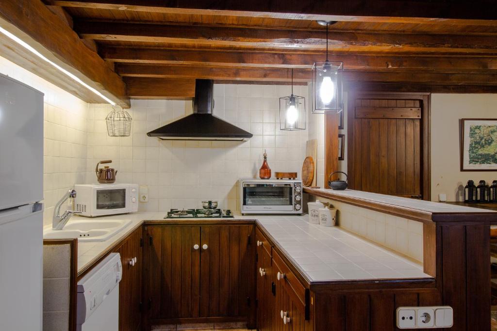 a kitchen with wooden cabinets and a stove and microwave at Maison en Cerdagne avec belle vue in Enveitg